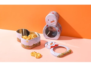 Close-up of snowman tin gift box with clear window and cookies on festive background