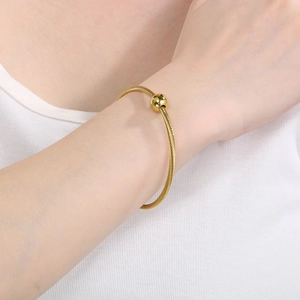 Detail of a twisted gold wire bracelet with a sliding bead on a woman's wrist