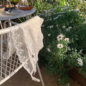Beige lace triangle headscarf with crochet floral edges in a romantic garden setting