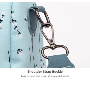 Detail of durable bronze metal strap hooks and leather trim on a floral Oxford backpack