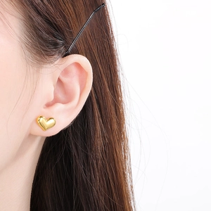 Close-up of 18K gold-plated heart-shaped stud earring worn by model with glossy finish
