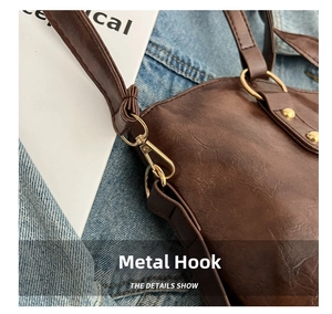 Close-up of vintage brown leather bag with golden metal hook and rivet details