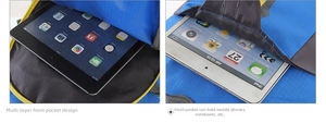 Detail of multi-layer front pockets on a blue nylon backpack holding a tablet device