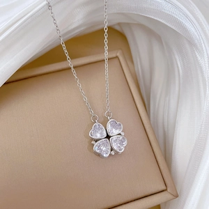 Silver four-leaf clover necklace with heart-shaped zircons in a jewelry box