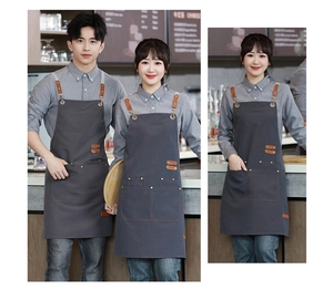 Detail of grey canvas apron with brown leather straps and metal buckles for baristas