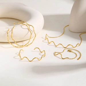 Macro shot of gold-plated wavy jewelry set including earrings, necklace and bracelet