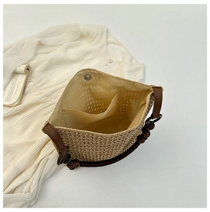 Detail view of woven straw tote bag featuring fabric lining and dark wood bead handles