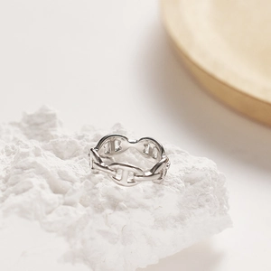 Polished titanium steel ring with pig nose link design on white textured stone