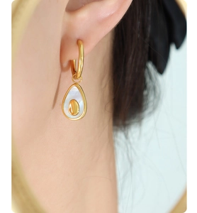 Close-up of elegant avocado-shaped shell earrings with gold metal on earlobe