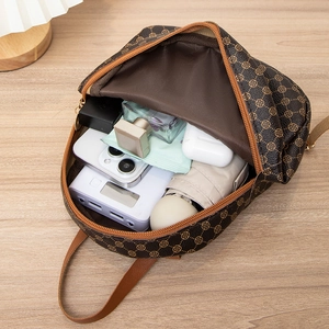 Brown vintage backpack with clover pattern showing large capacity on a wooden table
