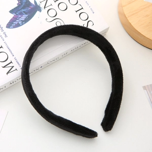 Détail du serre-tête large en velours noir sur bureau blanc avec décor de livre