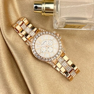 Close-up of golden rhinestone watch on luxury silk with perfume bottle backdrop