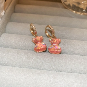Détail de boucles d'oreilles ours en résine rose avec crochets dorés sertis de strass