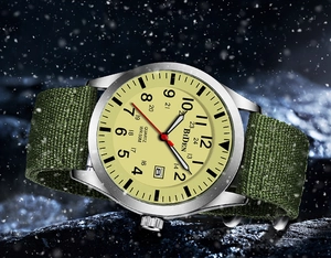 Detail of military quartz watch with yellow dial, green nylon strap, and date window