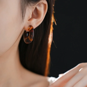 Close-up of leopard print resin C-shaped hoop earrings on model with soft lighting