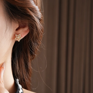Close-up of gold star earrings with pavé cubic zirconia worn by a female model
