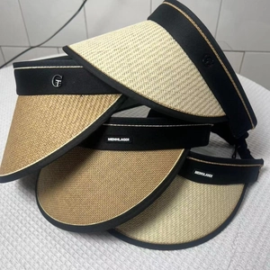 Detail of multi-color woven straw sun visors with flexible bands and metallic logo accents
