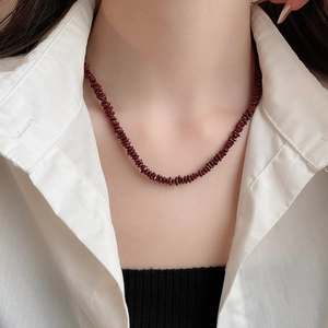 Close-up of deep wine red beaded necklace on model with elegant retro aesthetic