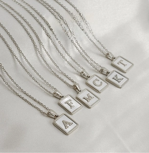 Detailed view of square silver necklaces with natural shell alphabet letter pendants
