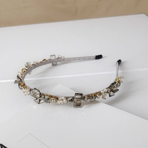 Macro detail of luxury crystal stones and white pearls on a light grey thin headband