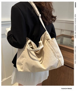 Macro view of cream white corduroy tote bag showing ribbed texture and shoulder straps