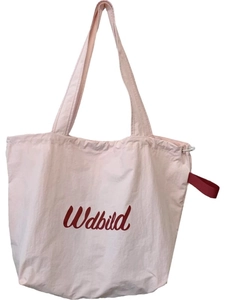 Light pink drawstring canvas tote bag with artistic lettering and red side straps