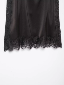 Détail du tissu satiné noir lisse et de la bordure en dentelle délicate sur l'ourlet