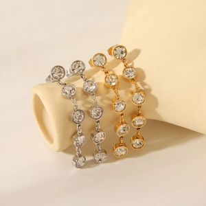 Macro view of gold and silver long tassel earrings with sparkling crystals on a ceramic stand