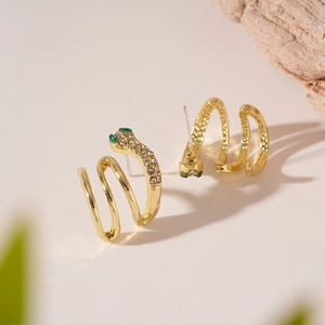 Detail of gold snake earrings with sparkling rhinestones and green gemstone eyes