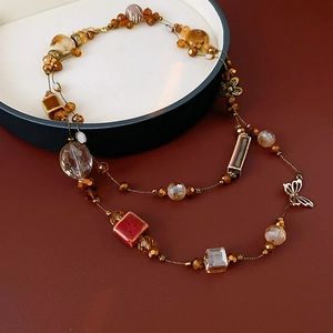 Détail d'un collier en perles de céramique marron avec breloques dorées sur un plateau