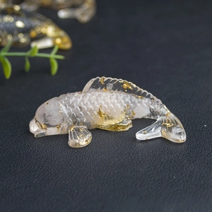 Close-up of transparent koi fish resin ornament with gold foil flakes on black background