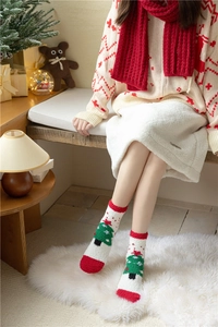 Détail de chaussettes de Noël en polaire corail avec motif sapin vert et bordure rouge
