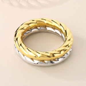 Detail of gold and silver twisted croissant rings on a warm beige background