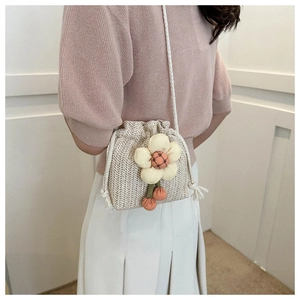 Mini borsa a secchiello in paglia con fiori indossata da modella in abiti casual