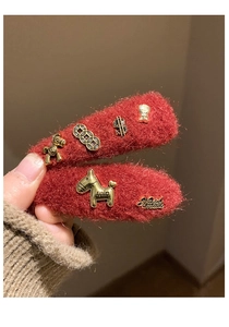 Detail of red plush hair clips featuring vintage gold horse charms and metal coin pendants
