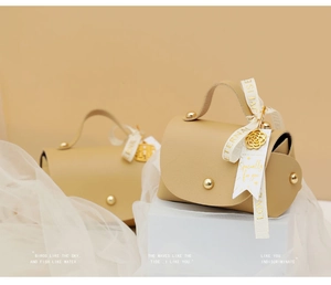 Detail of cream faux leather wedding favor bags with gold hardware and silk ribbons