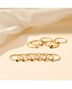 Macro detail of slim gold stainless steel rings featuring colorful round gemstones