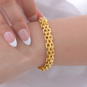 Close-up of a wide gold stainless steel interlocking chain bracelet on a male wrist