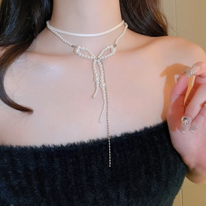 Close-up of double-layer choker featuring a white satin ribbon and pearl bow with tassels