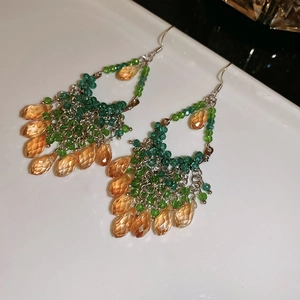 Detail of bohemian long tassel earrings with amber faceted beads and green accents