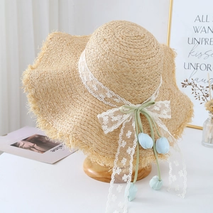 Beige straw sun hat with white lace ribbon bow and tulip floral charms for beach vacations