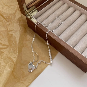 Detailed shot of silver heart and star necklace with white pearls on a wooden jewelry box