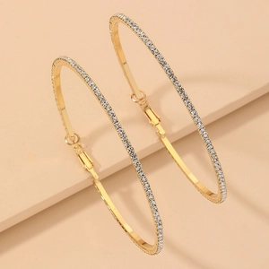 Detailed close-up of golden hoop earrings featuring micro-paved sparkling crystals