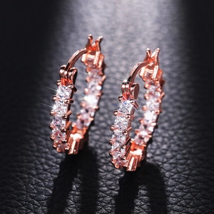 Luxury rose gold earrings with square-cut cubic zirconia on a black leather background