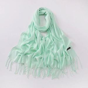Detail view of mint green cashmere scarf with fringe tassels and brand logo label