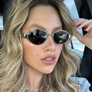 Close-up of stylish oval silver metal sunglasses with dark lenses worn by a fashion model