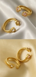 Macro detail of gold heart-shaped rings with sparkling zircons on elegant satin