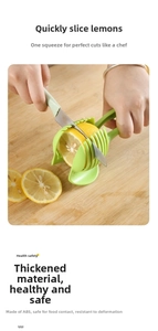 Close-up of a green ABS handheld lemon slicer guide tool on a wooden cutting board