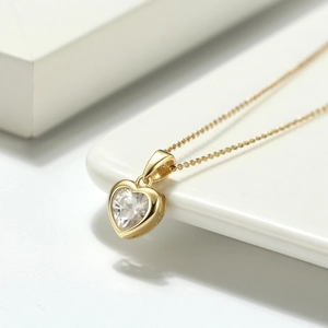 Gros plan du collier coeur en argent S925 avec zircon sur un socle blanc pur
