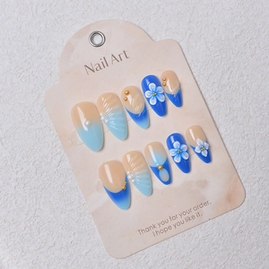 Dettaglio di unghie finte blu con fiori 3D e perle su cartoncino di presentazione